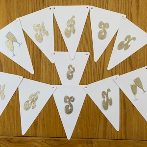 May include: White triangular paper bunting with gold glitter letters spelling out "MR & MRS" and a champagne glass design.