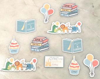 May include: A collection of stickers with a birthday theme. The stickers include images of books, cupcakes, balloons, and cartoon animals. Some stickers have the text "ONE", "The Tale of Connor", and "One-ce upon a time". The color palette includes pastel shades.