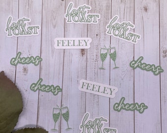 May include: A set of nine stickers with various designs, including the text "last toast", "cheers", and "feeley". The stickers are green and white and are on a wooden background.