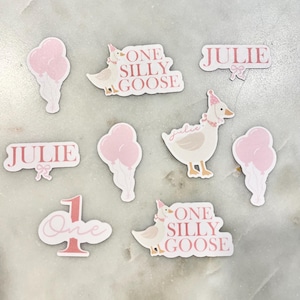 May include: Pink and white stickers with the text "One Silly Goose" and "Julie" and a cartoon goose with a party hat.