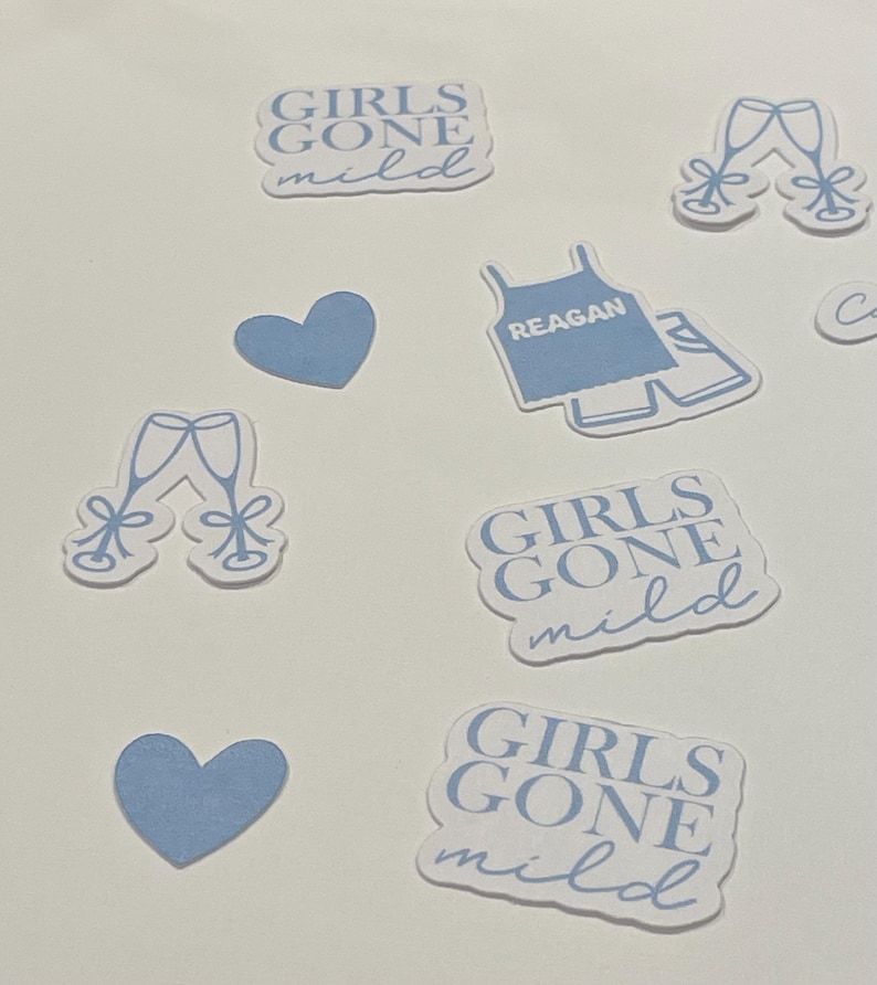 May include: A set of blue and white stickers with various designs, including two glasses of champagne, a heart, a tank top with the word "REAGAN" on it, and three stickers that say "GIRLS GONE MILD".