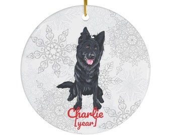 May include: A round ceramic ornament with a black German Shepherd dog sitting on a white snowflake background. The dog's name, "Charlie", and the year are written in red below the dog.