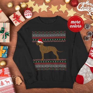 May include: Black Christmas jumper featuring a brown and white dog wearing a Santa hat. The jumper has a red, white and green pattern with candy canes and Christmas trees.
