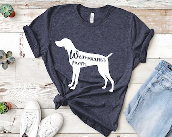 May include: A navy blue t-shirt with a white silhouette of a Weimaraner dog and the text "Weimaraner mom".