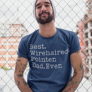Pode incluir: Uma camiseta azul marinho com texto branco que diz "Best Wirehaired Pointer Dad Ever."