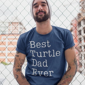 May include: A navy blue t-shirt with white text that reads "Best Turtle Dad Ever".