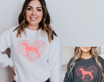 May include: White sweatshirt with a pink floral heart design featuring a dog silhouette. The heart design is centered on the chest of the sweatshirt. The sweatshirt is being modeled by a person wearing blue jeans.