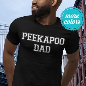 Puede incluir: Una camiseta negra con el texto "PEEKAPOO DAD" en letras blancas.