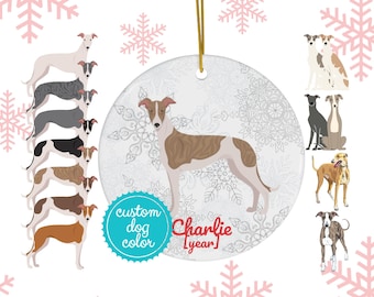 Könnte beinhalten: Ein weißer Keramik-Weihnachtsbaumschmuck mit einer Illustration eines braunen und weißen Windhundes. Der Anhänger hat ein Schneeflockenmuster und den Text "Charlie [Jahr]" und "Individuelle Hunde Farbe".