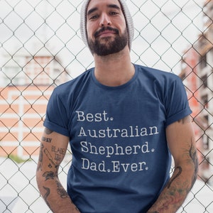 May include: A man wearing a blue t-shirt with white text that reads "Best Australian Shepherd Dad Ever".