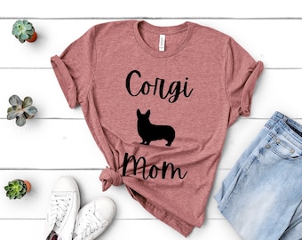 May include: A heather pink t-shirt with a black silhouette of a corgi and the text "Corgi Mom".