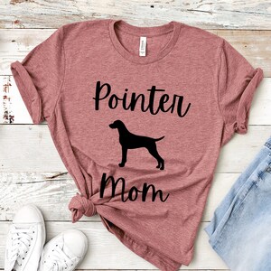 Pode incluir: Uma camiseta marrom-avermelhada com o texto "Pointer Mom" e uma silhueta preta de um cão pointer.
