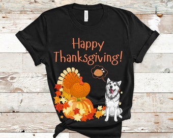 May include: Black t-shirt with the text "Happy Thanksgiving!" in orange. The shirt features a cartoon turkey, pumpkin, and a husky dog. The dog has a thought bubble with a turkey leg.