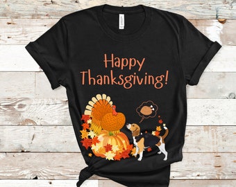 May include: Black t-shirt with a Thanksgiving design. The shirt features the text "Happy Thanksgiving!" in orange, along with a turkey, pumpkin, fall leaves, and a beagle dog dreaming of a turkey dinner.