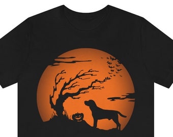 May include: A black short-sleeve t-shirt featuring a graphic print of a dog standing on a hill next to a bare tree and a jack-o'-lantern against a large orange full moon. A flock of bats is visible in the sky near the moon's upper edge.
