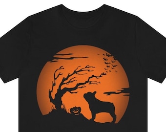 May include: A black short-sleeve t-shirt featuring a graphic print of a silhouette of a French bulldog standing next to a jack-o'-lantern and a bare tree against a large, circular orange full moon with a flock of bats flying in the sky.