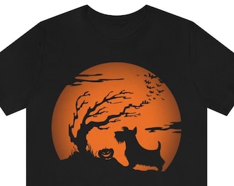 May include: A black t-shirt featuring a graphic print of a Scottish Terrier standing in front of a large orange full moon. The design includes a silhouette of a bare tree, a small jack-o'-lantern, and a flock of bats flying across the moon.