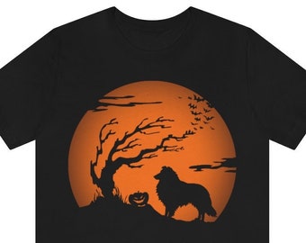 May include: A black short-sleeve t-shirt featuring a graphic print of a silhouette of a dog standing next to a jack-o'-lantern and a bare tree against a large, round, orange full moon with a flock of bats flying in the night sky.