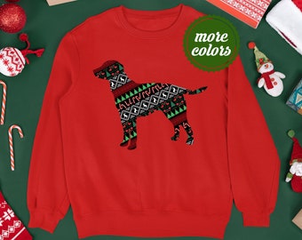 Può includere: Una felpa rossa con la silhouette di un cane decorata con un motivo festivo di alberi, renne e bastoncini di zucchero verdi, bianchi e neri. La felpa ha un girocollo e maniche lunghe. È visibile un cerchio verde con la scritta "more colors".
