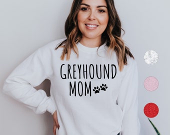 May include: White sweatshirt with the text "Greyhound Mom" and two paw prints in black.