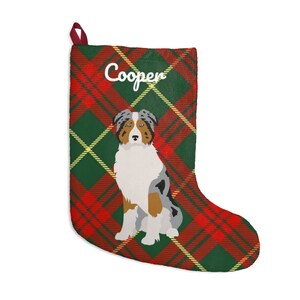 May include: Christmas stocking with a red, green, and yellow plaid pattern. The stocking features a seated dog illustration and the name "Cooper" in white script. A red loop is attached for hanging.