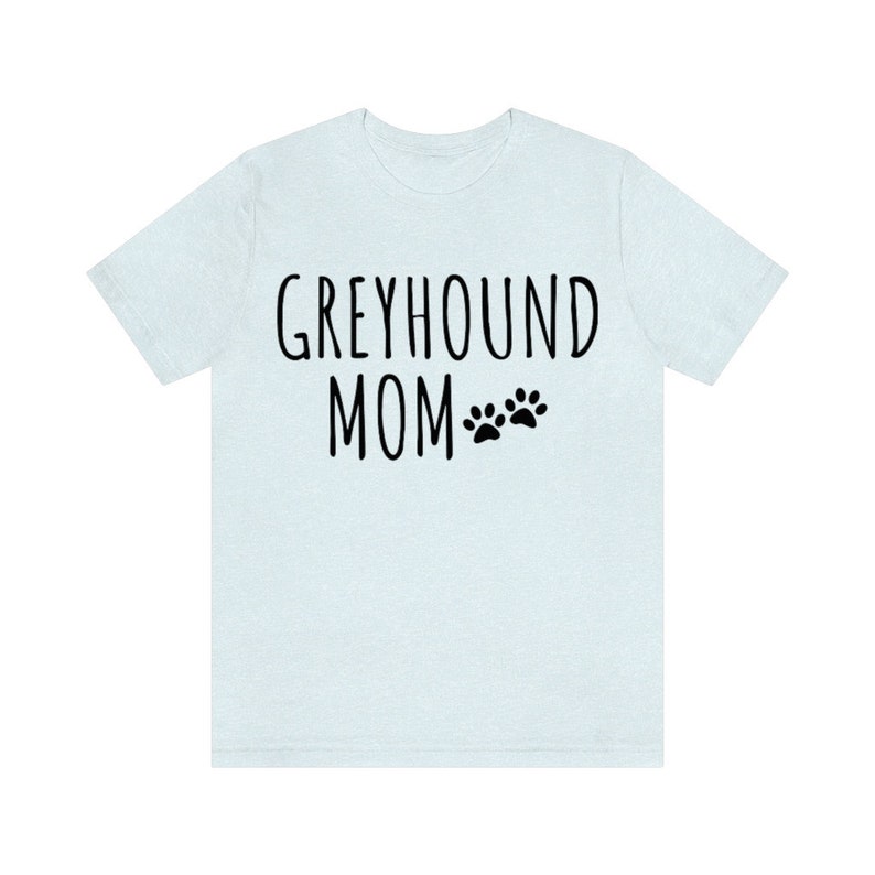 May include: Light blue t-shirt with the text "Greyhound Mom" and two black paw prints.