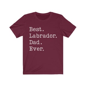 May include: Burgundy t-shirt with white text that reads "Best Labrador Dad Ever."  The text is in a typewriter font and includes paw prints.