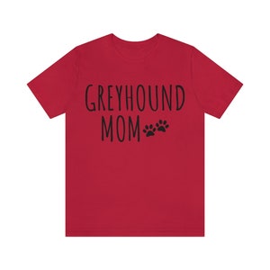 May include: Red short-sleeved t-shirt with the text "Greyhound Mom" and two black paw prints.