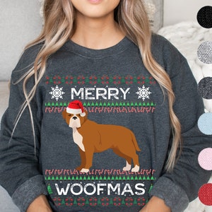 May include: Dark gray sweatshirt with a festive design. The design includes the words "MERRY WOOFMAS" with a brown dog wearing a Santa hat. The design also features snowflakes, candy canes, and Christmas trees.