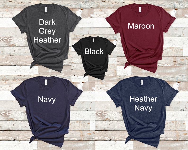 May include: Five t-shirts in different colors: dark grey heather, black, maroon, navy, and heather navy. Each shirt has a white text label with the color name.