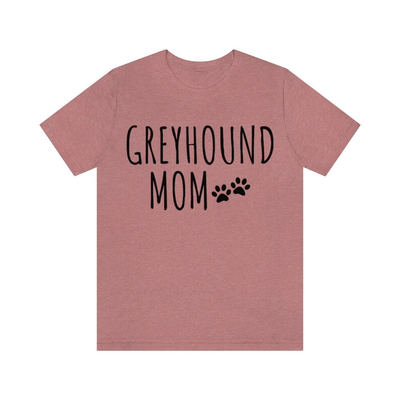 May include: A heather pink t-shirt with the text "Greyhound Mom" and two black paw prints.