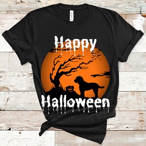 May include: Black t-shirt with a Halloween design. The design features a silhouette of a dog, a tree, and a pumpkin in front of an orange moon. The words "Happy Halloween" are written in white.