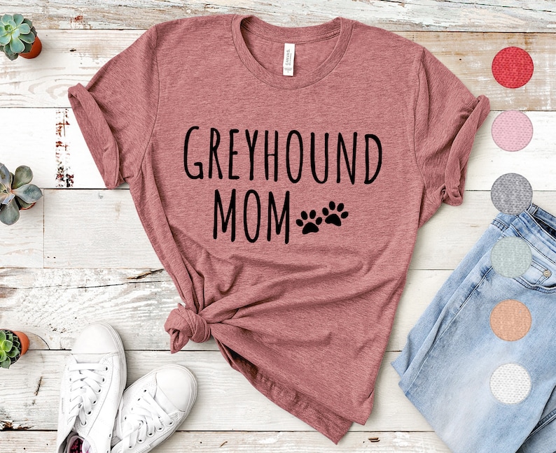May include: A heather pink t-shirt with the text "Greyhound Mom" and two paw prints in black.