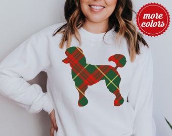 Puede incluir: Sudadera blanca con una silueta de caniche a cuadros rojos, verdes y amarillos. El diseño está centrado en la parte delantera de la parte superior de manga larga. Un círculo rojo con las palabras "more colors" está en la esquina superior derecha.