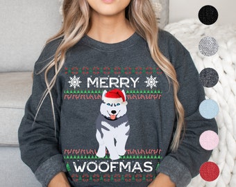 Puede incluir: Una sudadera gris oscuro con un diseño navideño festivo que presenta un perro husky con un gorro de Papá Noel. El texto "Merry Woofmas" está impreso en la sudadera.
