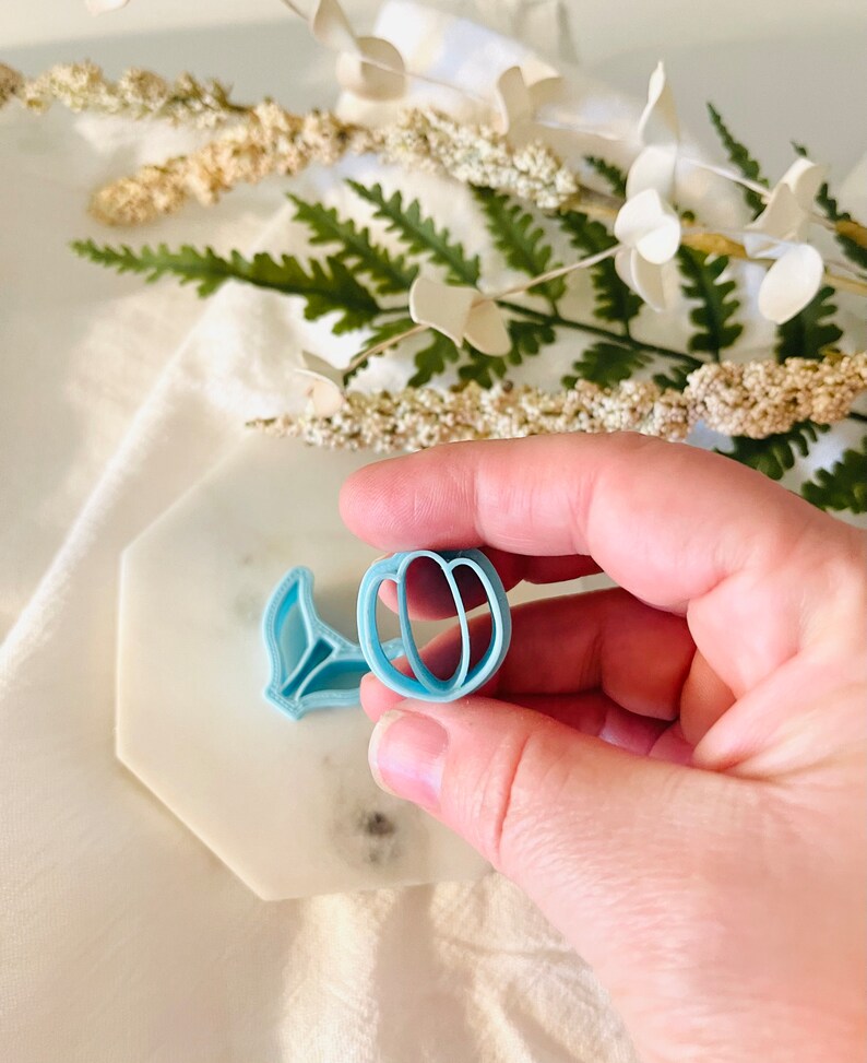 May include: A light blue plastic cookie cutter shaped like a peach with a leaf.