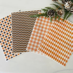 Op de afbeelding: Vier vellen decoratief papier met verschillende patronen. De patronen zijn zwart-oranje ruit, zwart-oranje chevron, oranje-wit geruit en oranje-wit diamant.