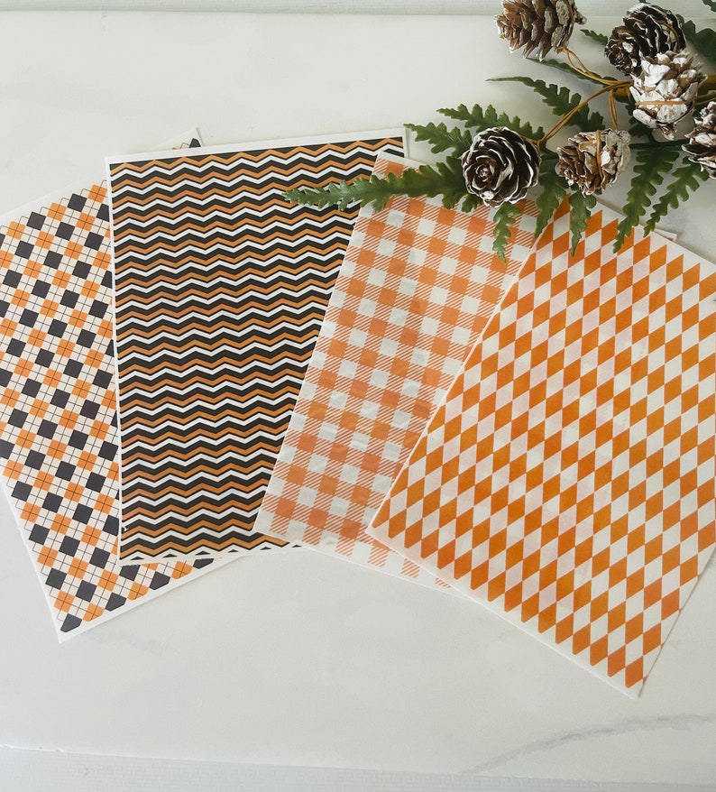 Op de afbeelding: Vier vellen decoratief papier met verschillende patronen. De patronen zijn zwart-oranje ruit, zwart-oranje chevron, oranje-wit geruit en oranje-wit diamant.