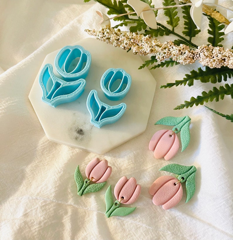 May include: A set of blue plastic tulip cookie cutters and three pink and green polymer clay tulip earrings.