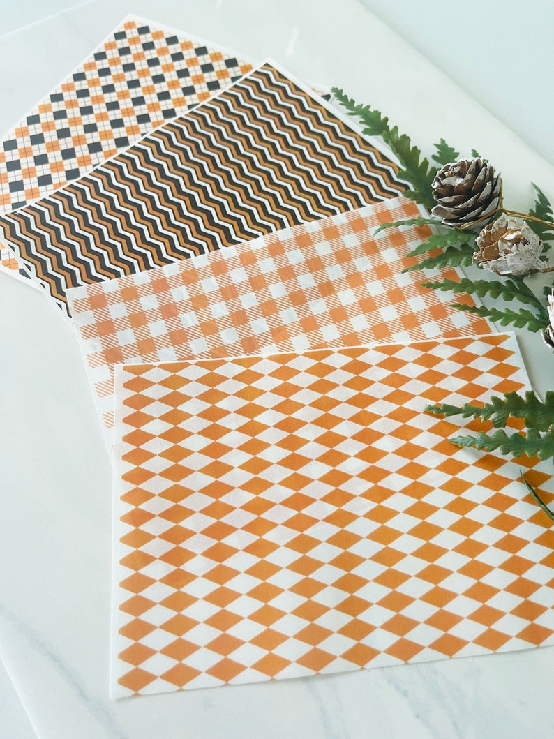 Op de afbeelding: Vier vellen decoratief inpakpapier met verschillende patronen. De patronen zijn zwart-oranje geruit, zwart-oranje golvende lijnen, wit-oranje geruit en wit-oranje ruitvormig.