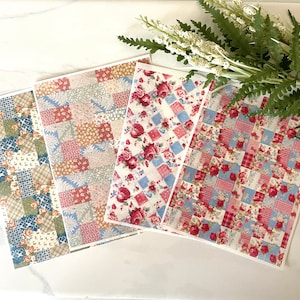 Peut inclure: Quatre carrés de tissu à motifs différents avec un design en patchwork. Les motifs présentent des motifs floraux rouges, bleus et blancs sur un fond blanc.