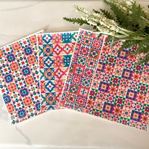 May include: Four colourful patterned paper sheets with geometric designs in shades of red, blue, green, and orange. The patterns are reminiscent of traditional quilt designs.