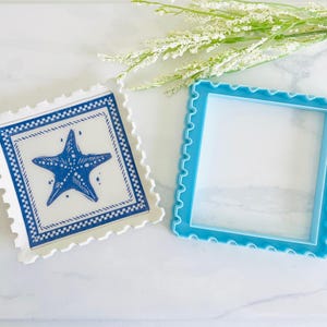 Pode incluir: Duas bases quadradas com um design semelhante a um selo. Uma base &eacute; branca com uma ilustra&ccedil;&atilde;o de estrela do mar azul e uma borda azul. A outra &eacute; uma moldura azul clara s&oacute;lida. Ambas t&ecirc;m uma borda ondulada. Decora&ccedil;&atilde;o costeira.