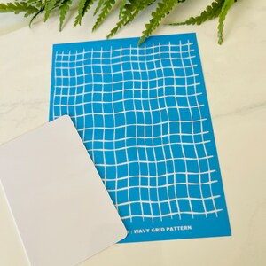 Może przedstawiać: Niebieski szablon z białym falistym wzorem siatki. Tekst "WAVY GRID PATTERN" jest nadrukowany na dole szablonu.