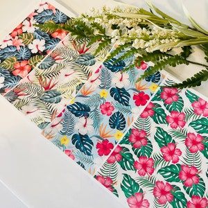 May include: Several sheets of patterned paper with tropical designs, including hibiscus flowers and palm leaves. The colour schemes vary, with pink, red, and blue hues. The papers are decorated with tropical floral and foliage patterns.