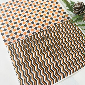 Op de afbeelding: Twee vellen met een geometrisch patroon in zwart, wit en oranje. Het bovenste vel heeft een geruit patroon en het onderste vel heeft een zigzagpatroon.