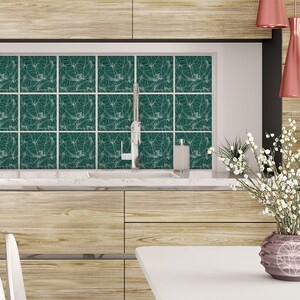 Peut inclure: Une cuisine avec une crédence en carrelage à motifs verts et blancs, un évier en acier inoxydable et un plan de travail en bois. Un vase avec des fleurs blanches est posé sur une table blanche au premier plan.