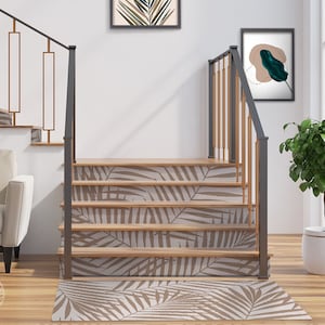 May include: A set of brown and white palm leaf patterned stair treads with a matching runner rug. The stair treads and rug are placed on a wooden floor in a modern home.