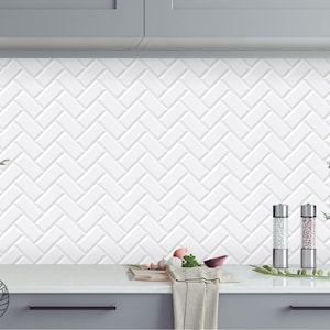 Pode incluir: Ladrilho de parede de cozinha branco com padrão de espinha de peixe. O ladrilho de parede é feito de azulejos de cerâmica e tem uma textura sutil em relevo. Há dois saleiros e pimenteiros no balcão em frente ao ladrilho de parede.