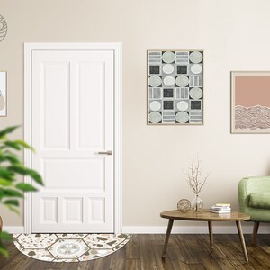 May include: A green sofa with a wooden coffee table in front of it. There is a white door, a rug with a geometric pattern, and three framed pictures on the wall behind the sofa.